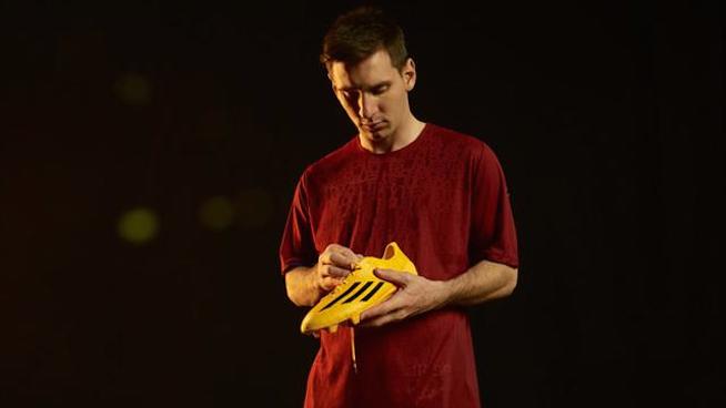 Lionel Messi examines his golden adidas signature cleat