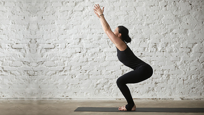 Young yogi attractive woman practicing yoga concept, doing advanced Chair exercise, Utkatasana pose, working out, wearing sportswear, black tank top and pants, full length, white loft background