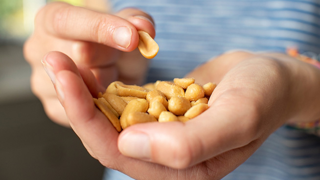 Close Up Of Teenage Girl Eating Handful Of Salted Peanuts