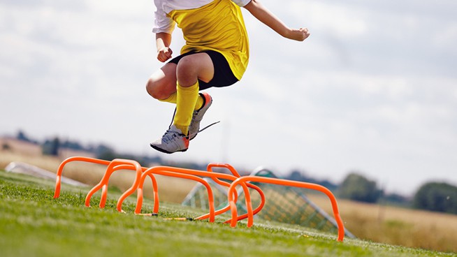 Young Sporty Boy Jumping Over Hurdles. Outdoor Soccer Agility Training on Summer Day. Football Practice Camp for Youth Teams