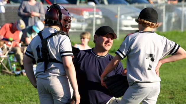 Parent talking to two youth baseball players