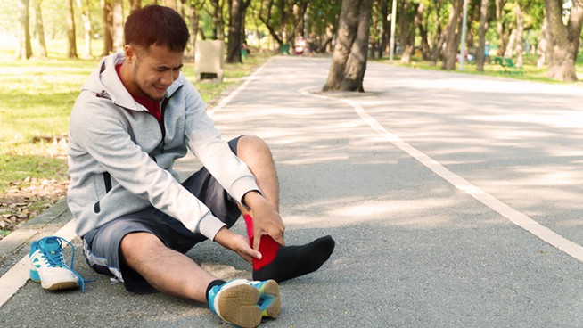 Athlete injured and grabbing ankle on outdoor basketball court