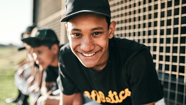 Portrait of a young baseball player sitting on a baseball field