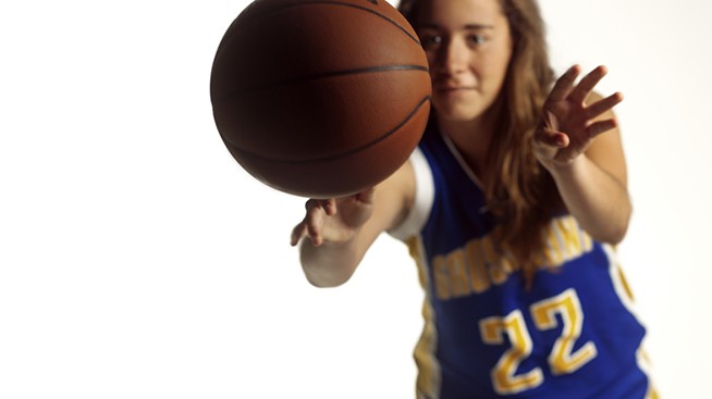 young female athlete passing a basketball