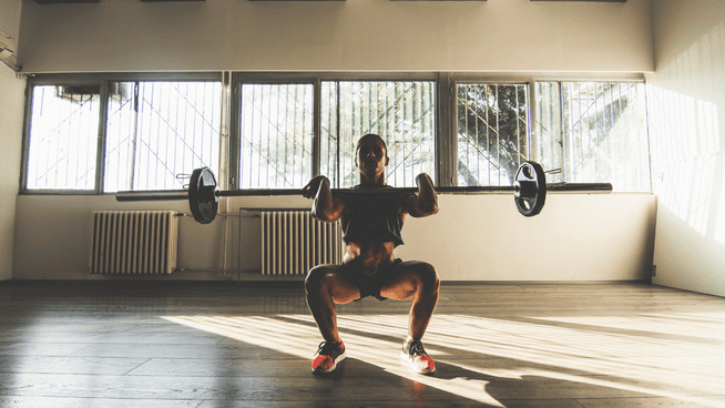athletic woman performing front squat in gym
