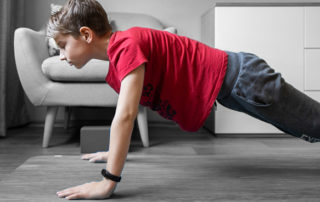 Small boy on yoga mat at home holding plank pose. Child physical activity at home on quarantine