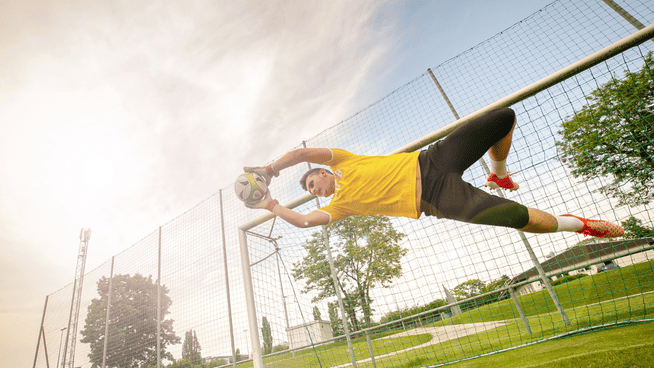 soccer goalkeeper or goalie saving ball from goal