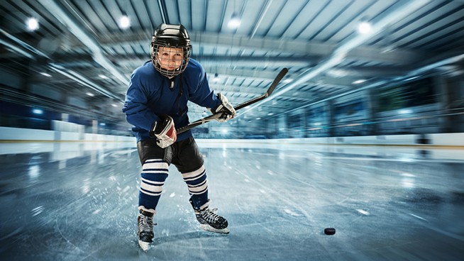 Young hockey player ready to make a strong shot against ice arena background