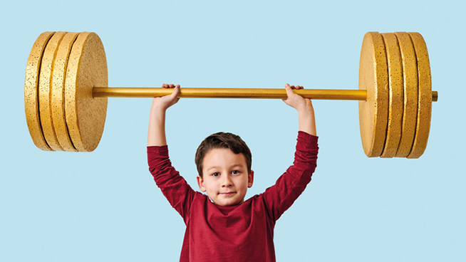 Cute child lifting gold barbell on blue pastel background. He is a determined and successful child.