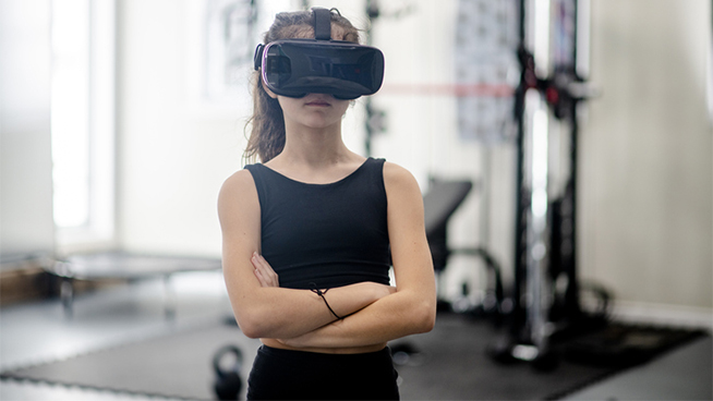 Young girl wearing a virtual reality headset while at the gym following a virtual fitness class.