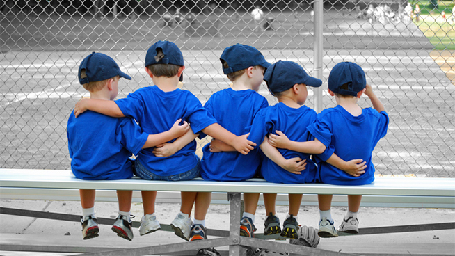 five little boys put their arms around each other befor their baseball game