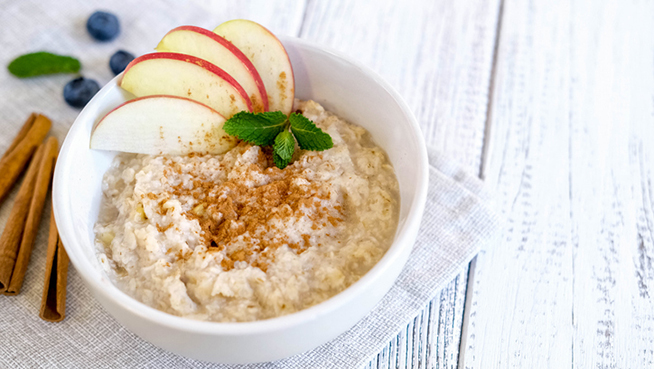 Delicious oatmeal with apple and cinnamon. Fresh natural breakfast served on wooden table