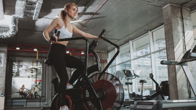 Woman working out on air bike at gym