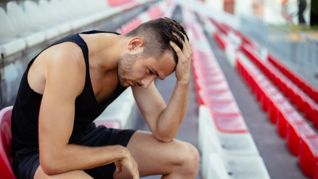 athlete sitting in bleachers with stress