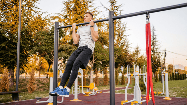 athletic male doing chin-ups in the park