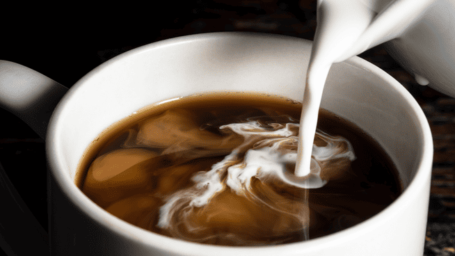 coffee creamer being poured into coffee close up shot
