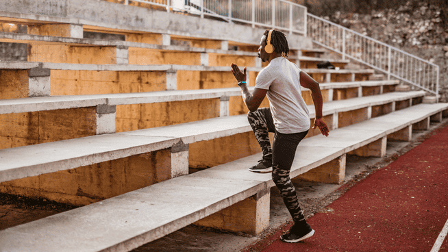 male athlete training by running bleachers at football stadium