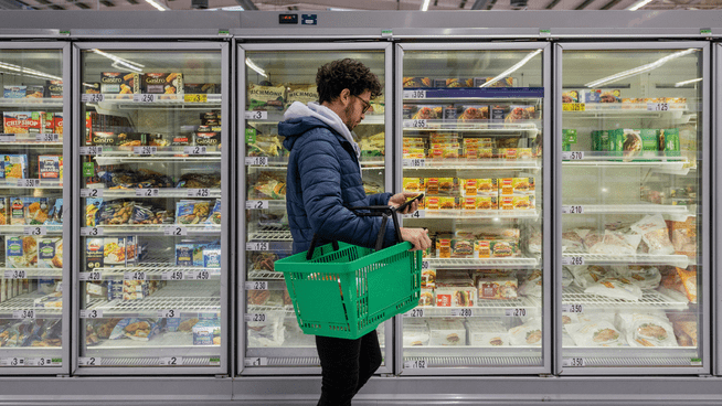 man searching for healthy processed foods at frozen foods section of grocery store