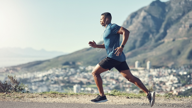 male runner training outside on hill with city in the mountains in the background - marathon and half-marathon training - how to run faster