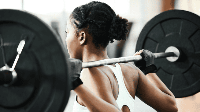 athletic woman lifting weights and doing squats in weight room