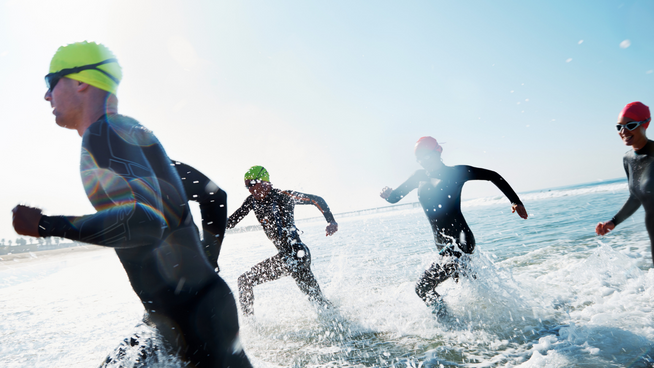 triathalon athletes in wetsuits running in water and competing - triathlete weight training