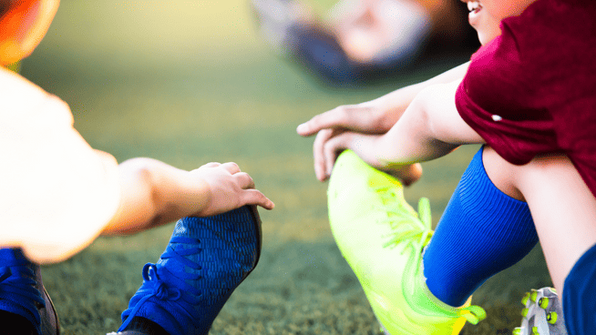 two young soccer players stretching during warmups