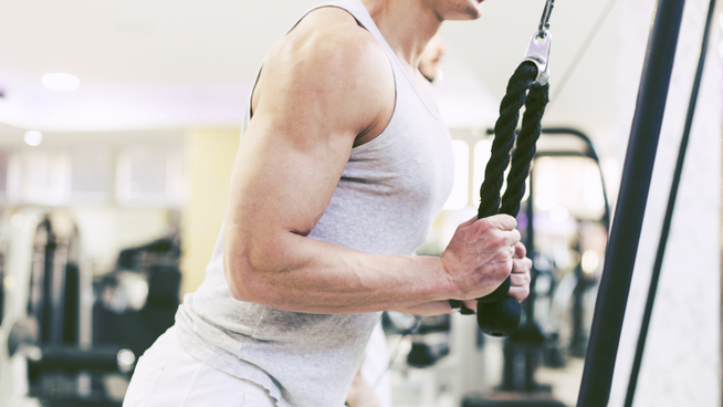 male athlete performing triceps pull downs at gym doing agonist antagonist training or ATT