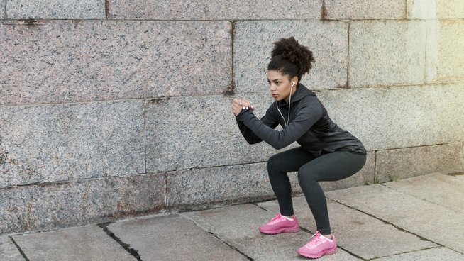 athletic woman performing a squat exercise on pavement outside