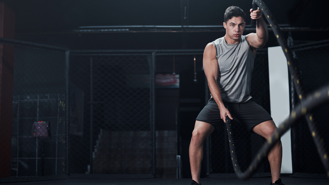 male athlete working out with the ropes at gym