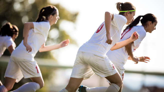female soccer athletes running on field