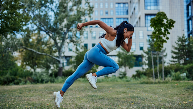 athlete female sprinting fast on grass outside in city