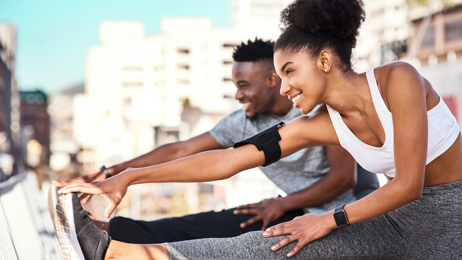 male and female athlete performing warm-down outside after workout