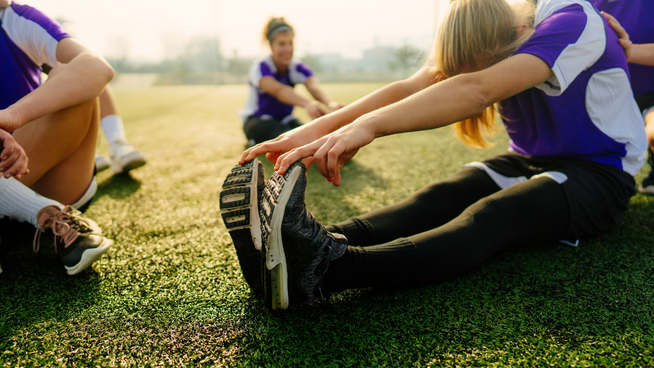 female youth soccer players stretching and warming up on the field before a game