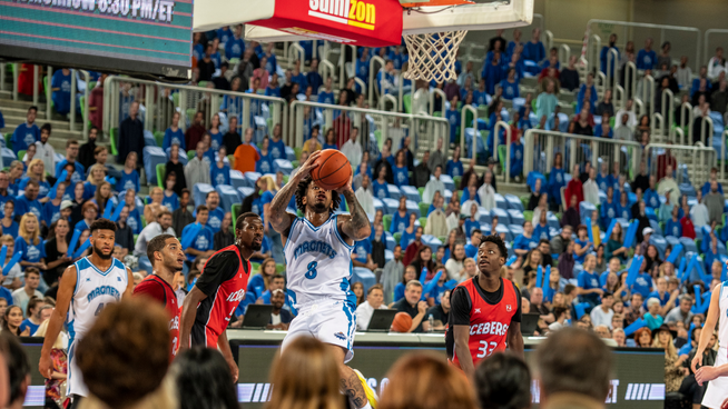 college basketball player jumping with big vertical in basketball game in front of fans