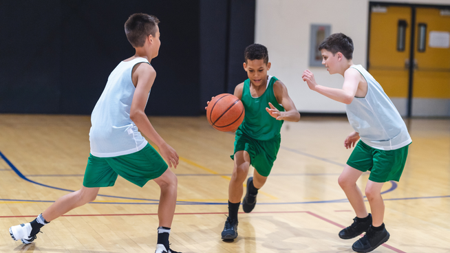 youth basketball players in a zone defense defending a dribbler on basketball court