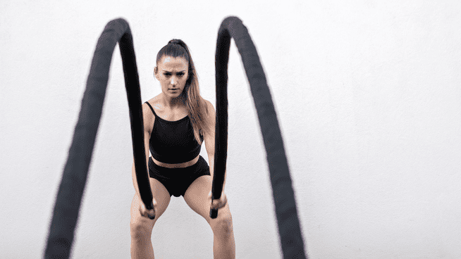 athletic woman training with battle ropes