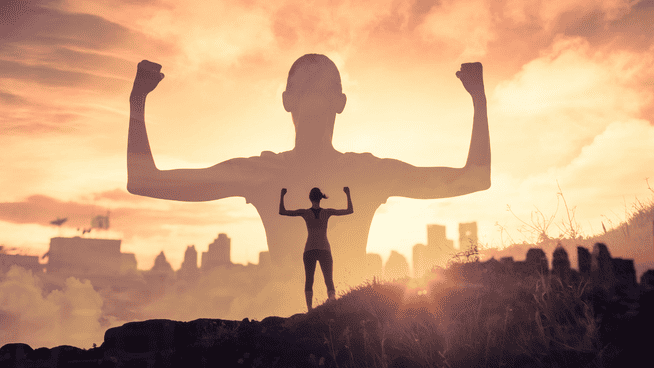 athletic woman flexing outside on a hill with large shadow of her in the clouds