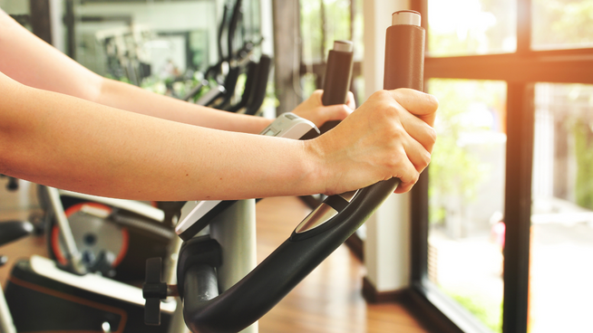 womans arms and hands on bicycle machine at gym while working out