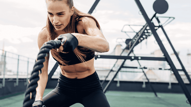 athletic woman on the battle ropes during a gym workout