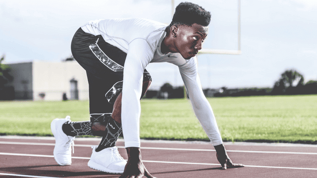 athletic male in sprinter position on track