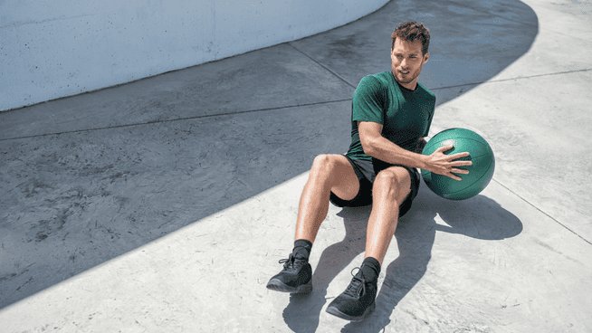 male athlete training with medicine ball outside