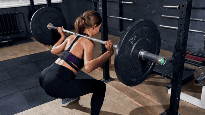woman performing squats at the gym at the bottom of her squat