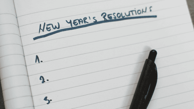 pen and pad that says new year's resolutions on it