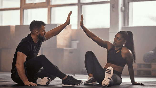 male and female athletes high fiving each other at the gym after fitness workout