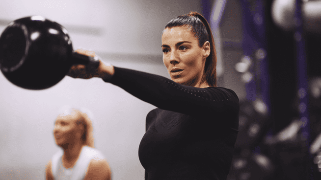 athletic female working out at gym with kettlebell