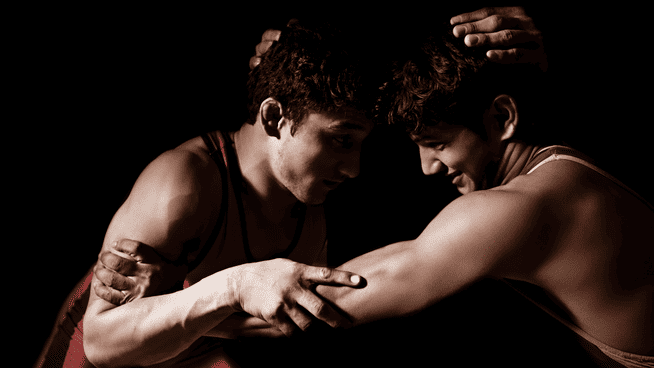 two youth athletes wrestling in competition with black background