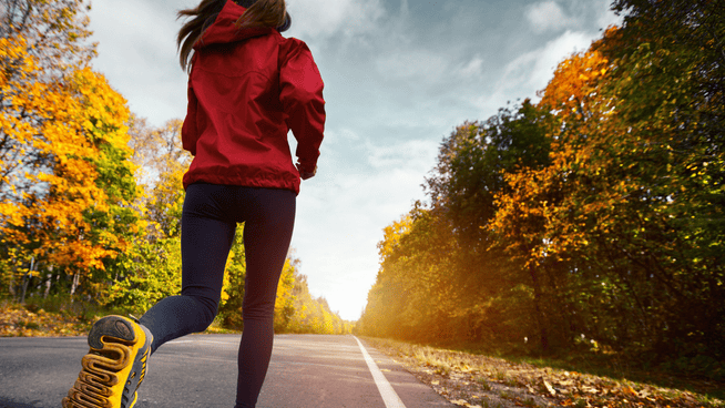 young woman distance running outside in beautiful fall weather