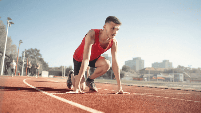 young male athlete lining up on track to sprint