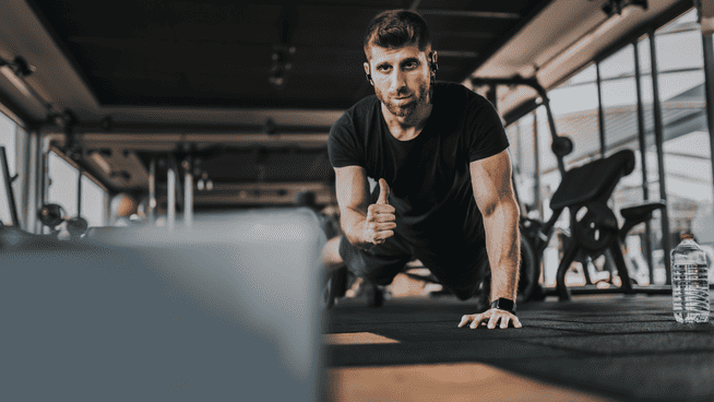 athletic male working out on computer with online personal trainer at gym