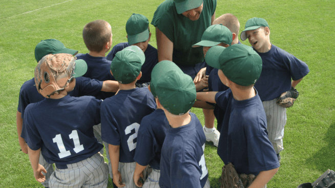 youth sports male baseball team in huddle with coach